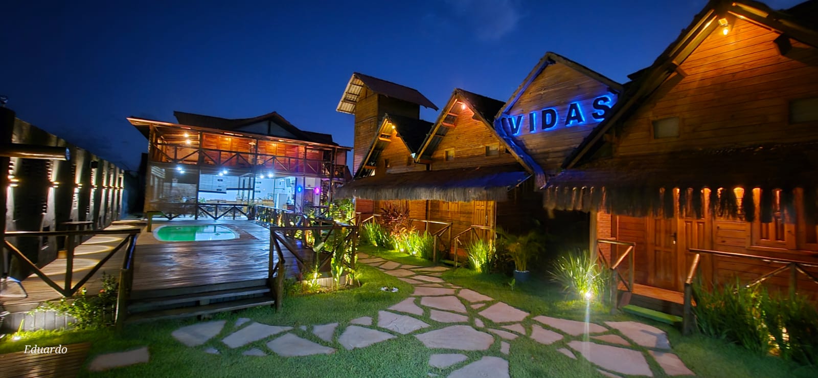 Fachada noturna iluminada com letreiro VIDAS